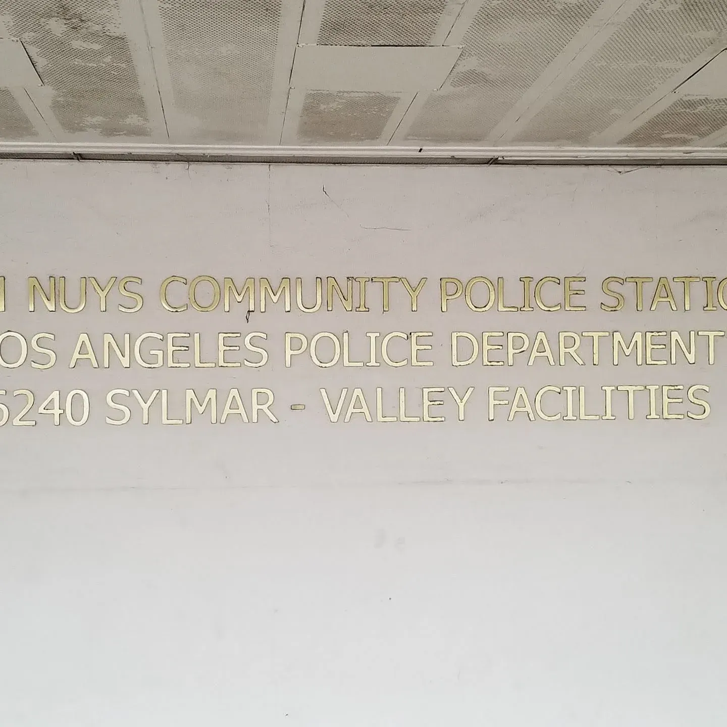 Gold letters on a wall sign for LAPD North Hollywood Community Police Station and Valley facilities