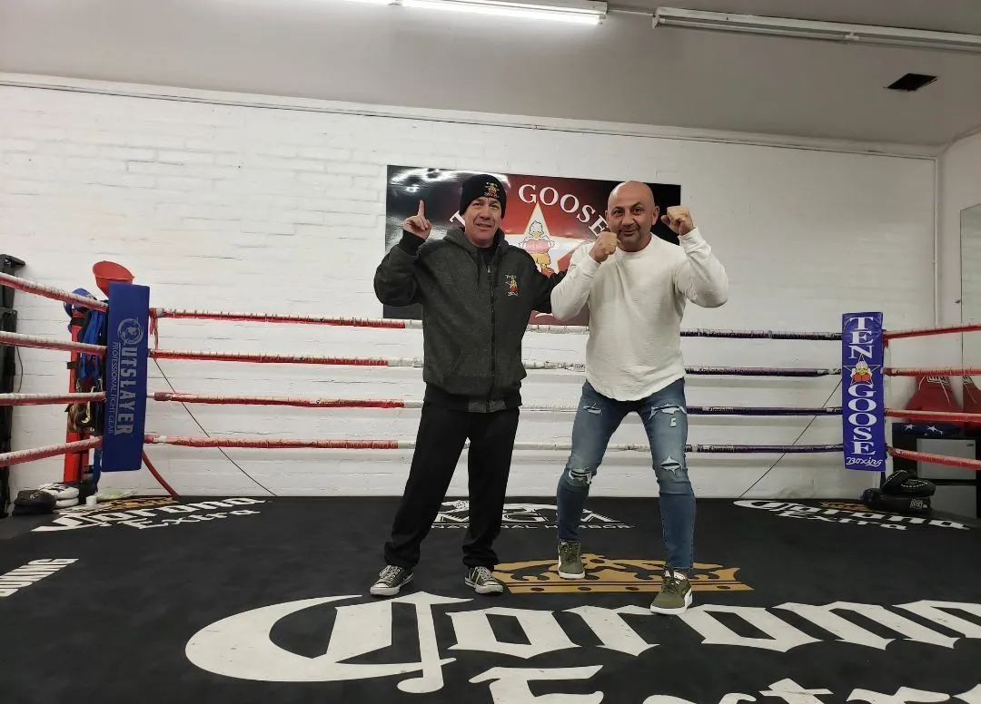 Two men are standing in a boxing ring with the word corona on the floor